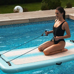 Femme utilisant un élastique de musculation sur aquaboard en piscine